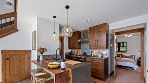 Una cocina moderna con una isla central, armarios de madera e iluminación colgante.