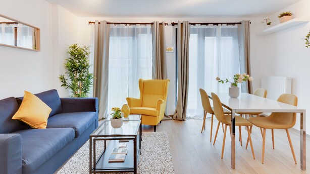 Een moderne woonkamer met een bank, fauteuil, eettafel en stoelen.