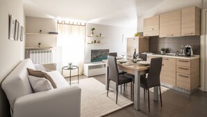 Une cuisine moderne avec des meubles en bois, un coin repas avec une table et des chaises, et un salon avec un canapé et une table basse.