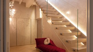 Une pièce moderne avec un escalier en verre, un canapé rouge et un plancher en bois.