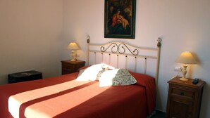 Un dormitorio con una cama, dos mesitas de noche, una lámpara en cada una y un cuadro en la pared.