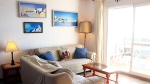 Una sala de estar con un sofá, una mesa de centro, una lámpara y tres cuadros en la pared.