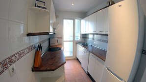 Una cocina con armarios blancos, encimera marrón y horno empotrado.