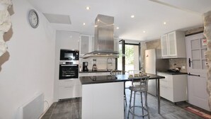 A modern kitchen with white cabinetry, a central island, stainless steel appliances, and a large window providing natural light.