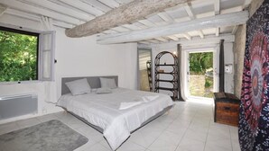 A bedroom with a large bed, a window, and a door leading to an outdoor area.