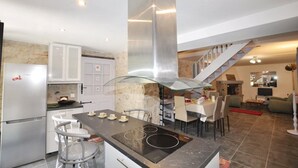 A modern kitchen with a central island, stainless steel appliances, and a staircase leading to an upper level.