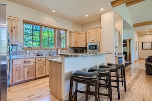 A kitchen with wooden cabinets, a granite countertop, a microwave, and a large window. - Highlands Vista | VIP Shuttle Service | Hot Tub! (Breckenridge)
