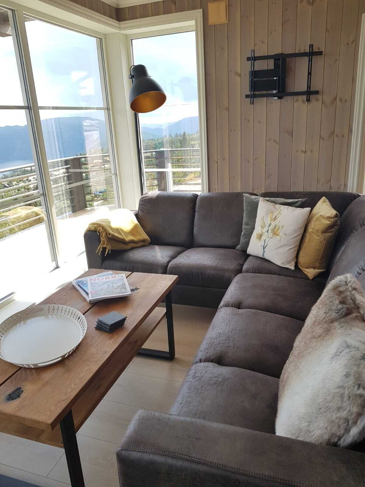 Un soggiorno moderno con un divano componibile, un tavolino in legno e un'ampia finestra con vista panoramica.