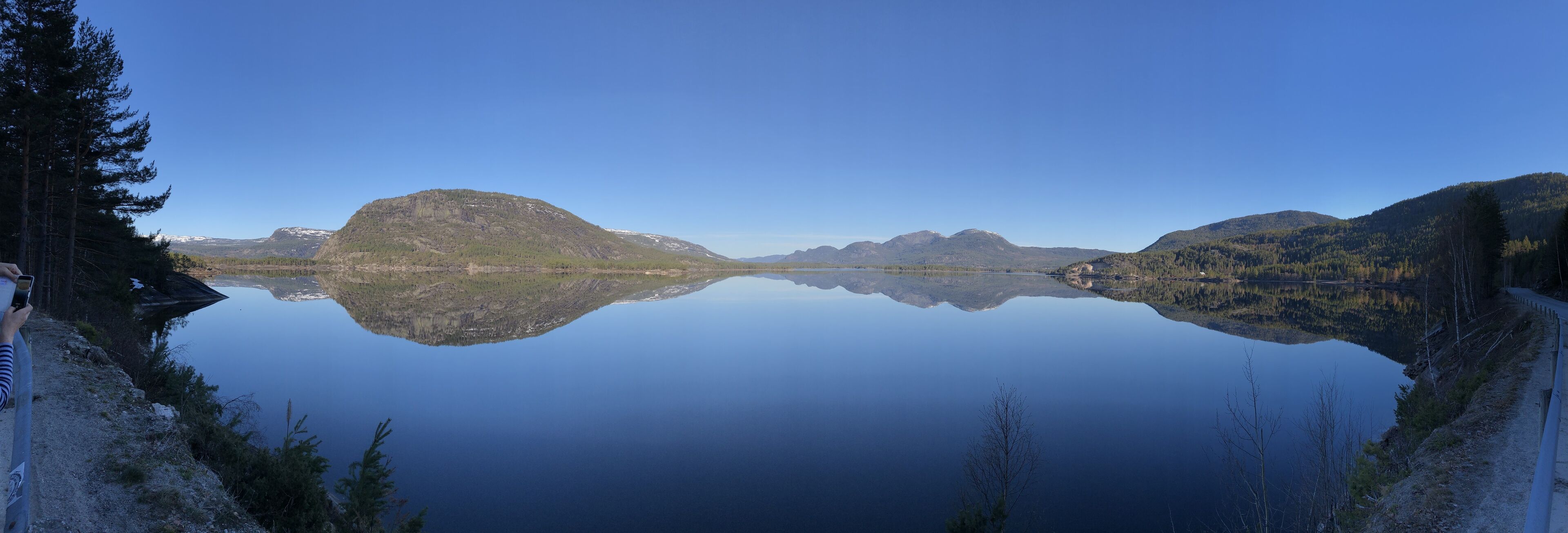 A calm lake with mountains in the background and a clear sky.