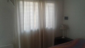 A room with a bed, a nightstand with a lamp, and sheer curtains. - Central Apartment Mendoza City (Mendoza)