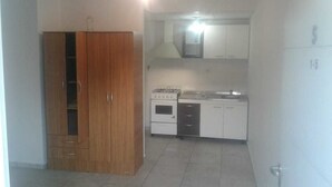 A compact kitchen with a stove, oven, and white cabinets. - Central Apartment Mendoza City (Mendoza)