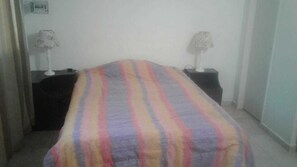 A room with a bed covered in a striped blanket, two bedside tables with lamps, and a wall-mounted thermostat. - Central Apartment Mendoza City (Mendoza)