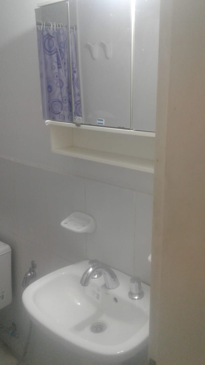 Un baño con un lavamanos blanco, un espejo encima y una cortina de ducha morada.
