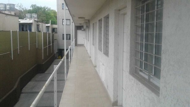 A narrow corridor with a tiled floor, white walls, and barred windows. - Central Apartment Mendoza City (Mendoza)