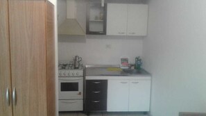 A compact kitchen with white cabinets, a stove, and a sink. - Central Apartment Mendoza City (Mendoza)