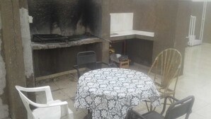 A room with a grill, a round table with a patterned tablecloth, and several chairs. - Central Apartment Mendoza City (Mendoza)