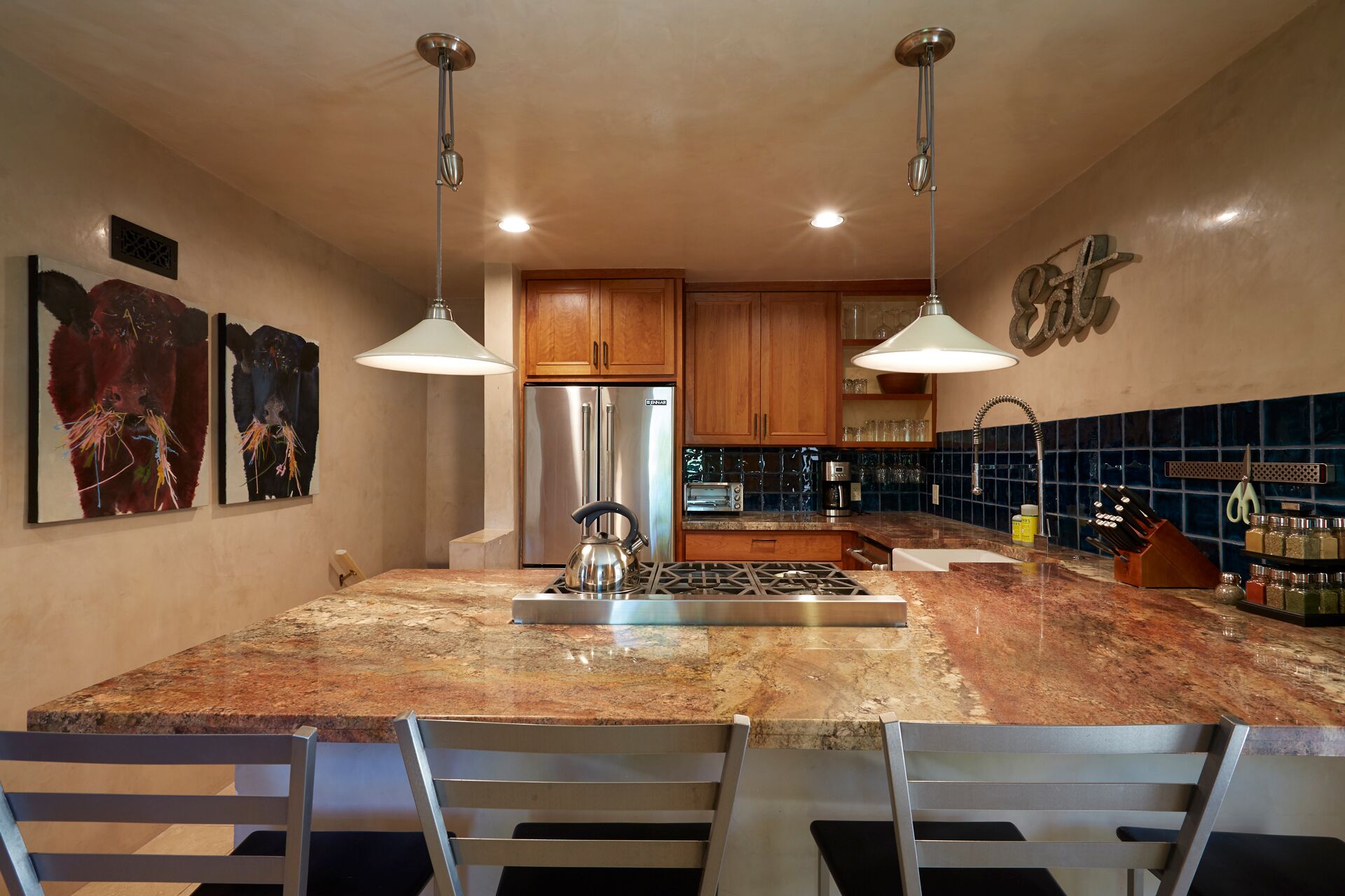 A modern kitchen with granite countertops, stainless steel appliances, and pendant lighting.