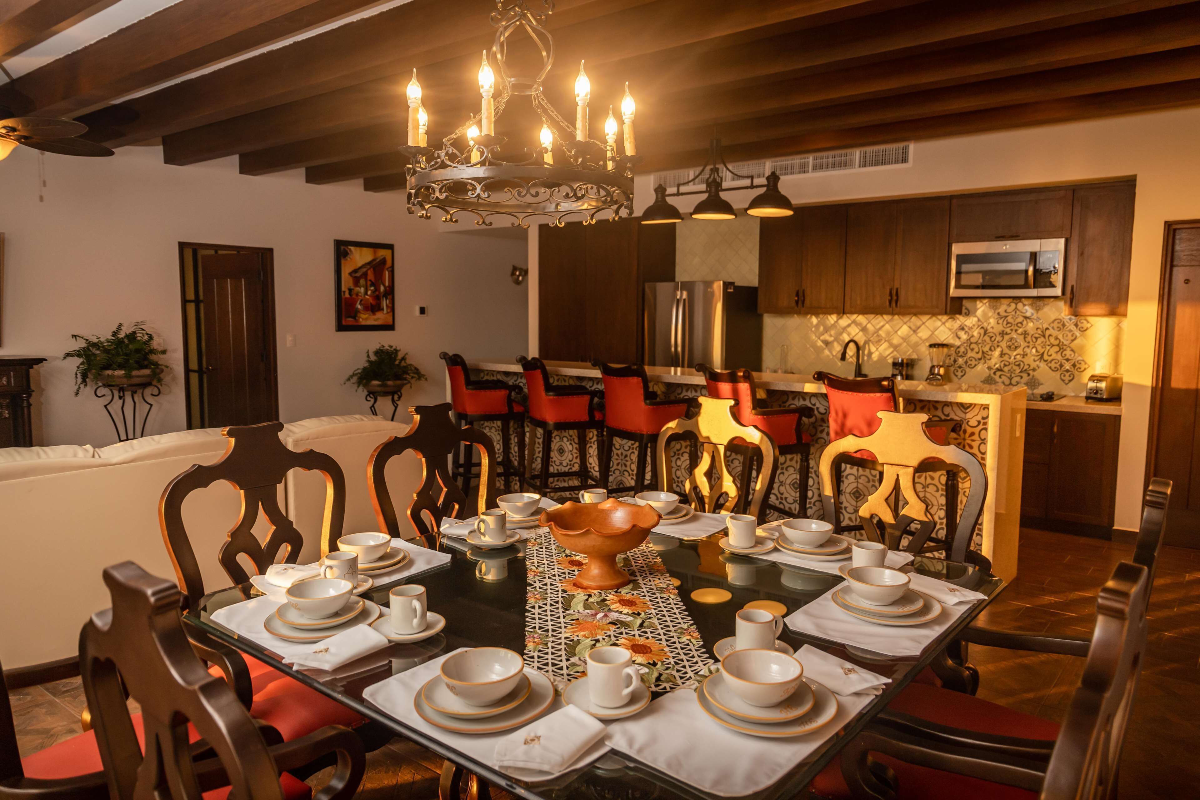 A dining area with a chandelier, wooden chairs, and a table set for a meal.