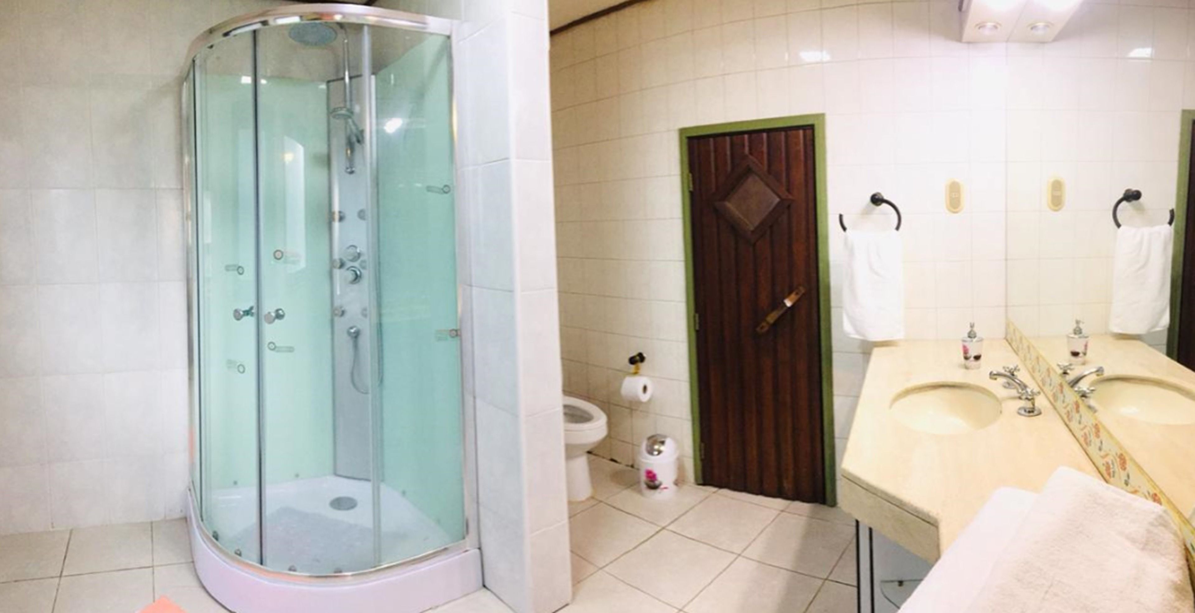 A bathroom with a glass-enclosed shower, a toilet, and a sink with a mirror.