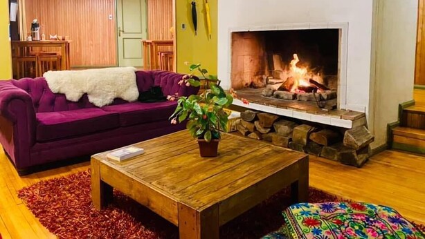 Uma sala de estar acolhedora com lareira, um sofá roxo e uma mesa de centro de madeira.