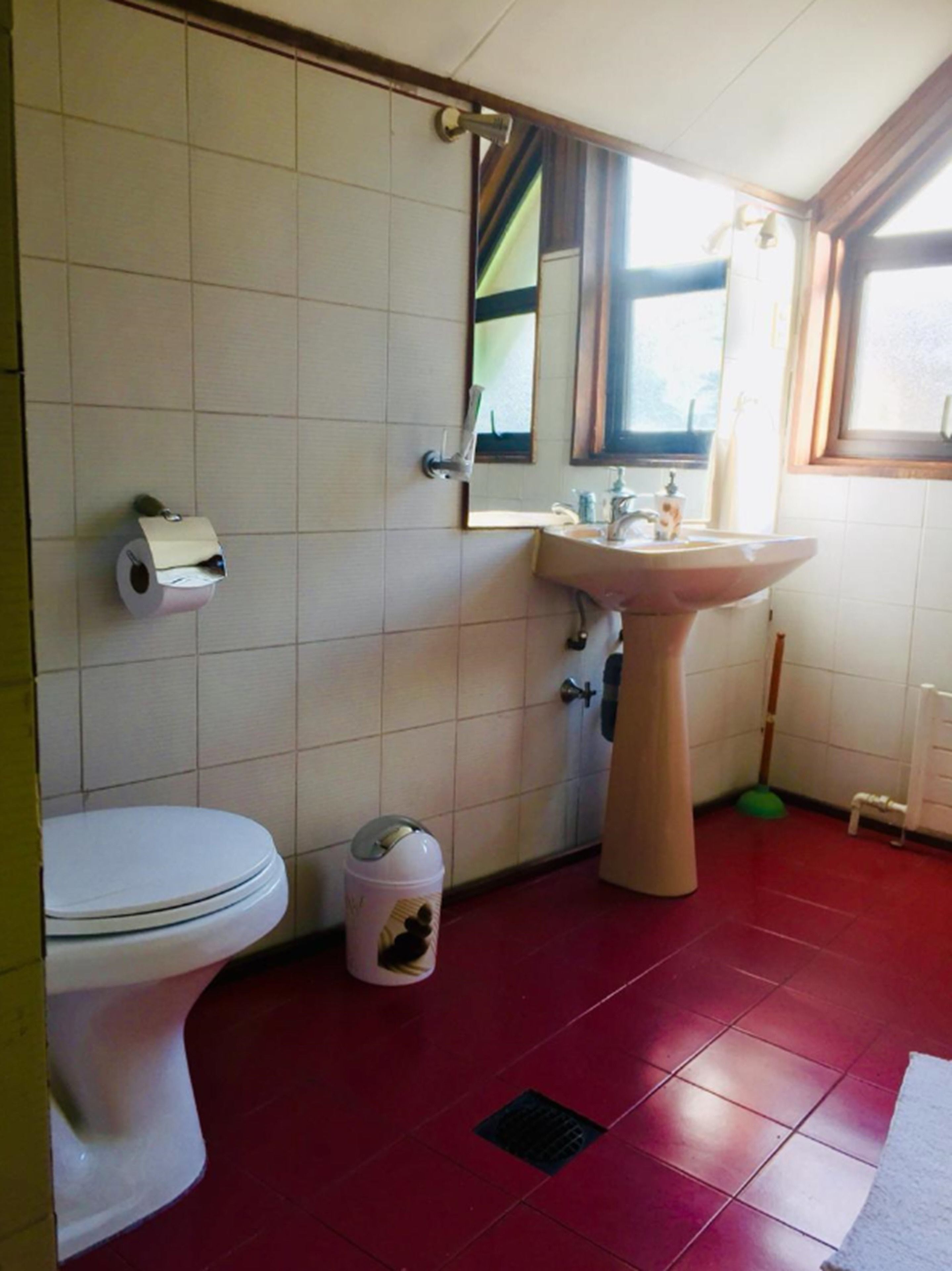 Un baño con inodoro, lavamanos, espejo y ventana.