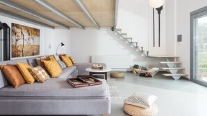 A modern living room with a grey sofa, a coffee table, and a staircase leading to an upper level.
