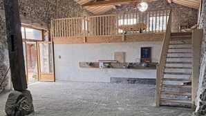 Een rustieke kamer met een stenen muur, een houten trap en een houten leuning.