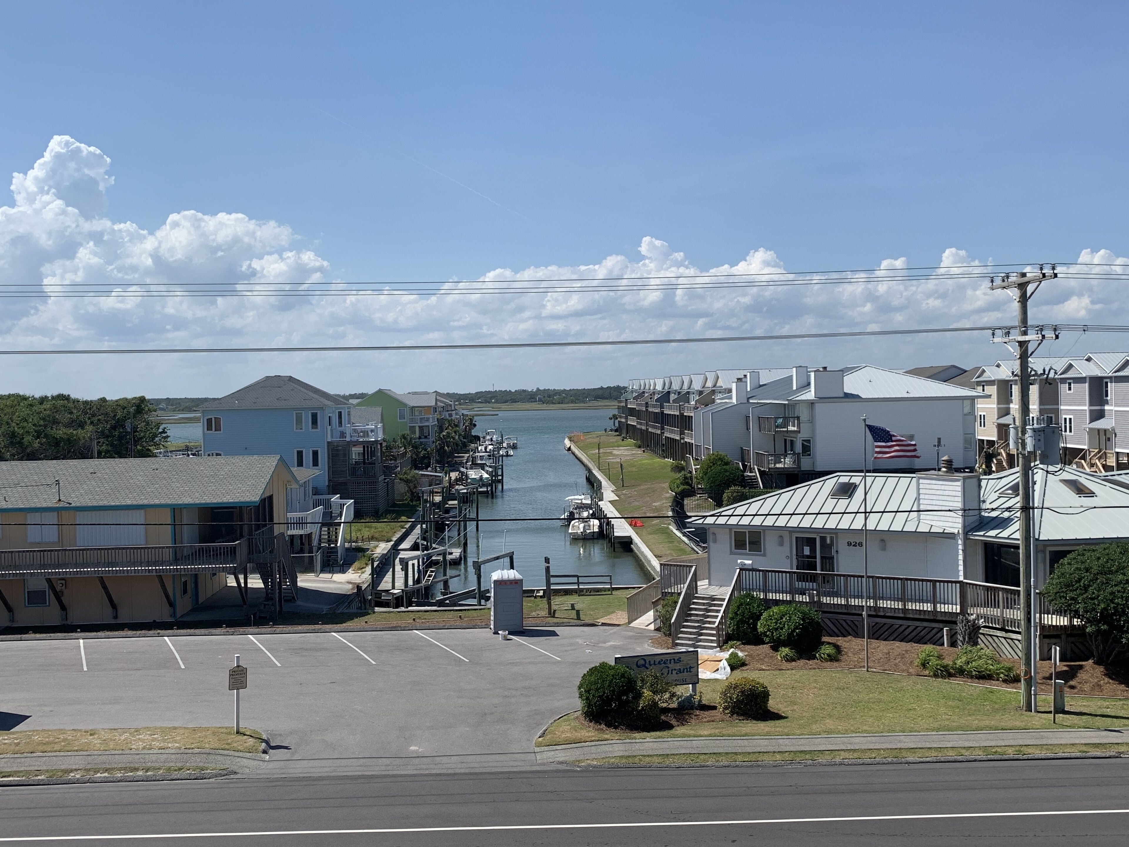A waterfront property with a marina, a parking lot, and a building with a flag.