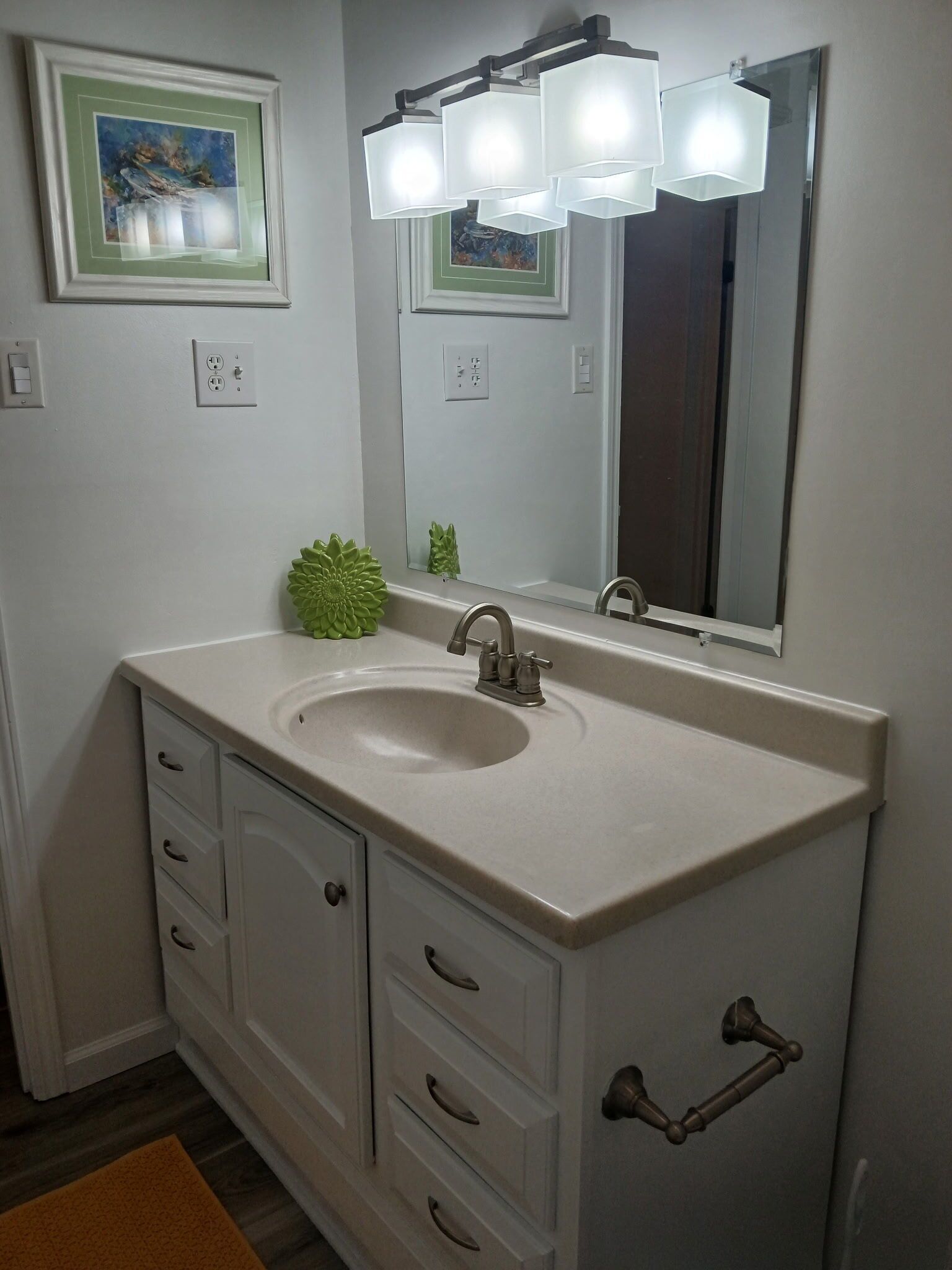 Une salle de bain avec un lavabo blanc, un grand miroir et une plante verte décorative.