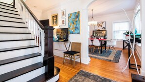 A spacious living area with a wooden staircase, a dining table with chairs, and a kitchen area with a stove and counter. - Hot tub, Highlands-Restaurant Row Churchill Downs, Zoo, Bellarmine, Downtown (Louisville)
