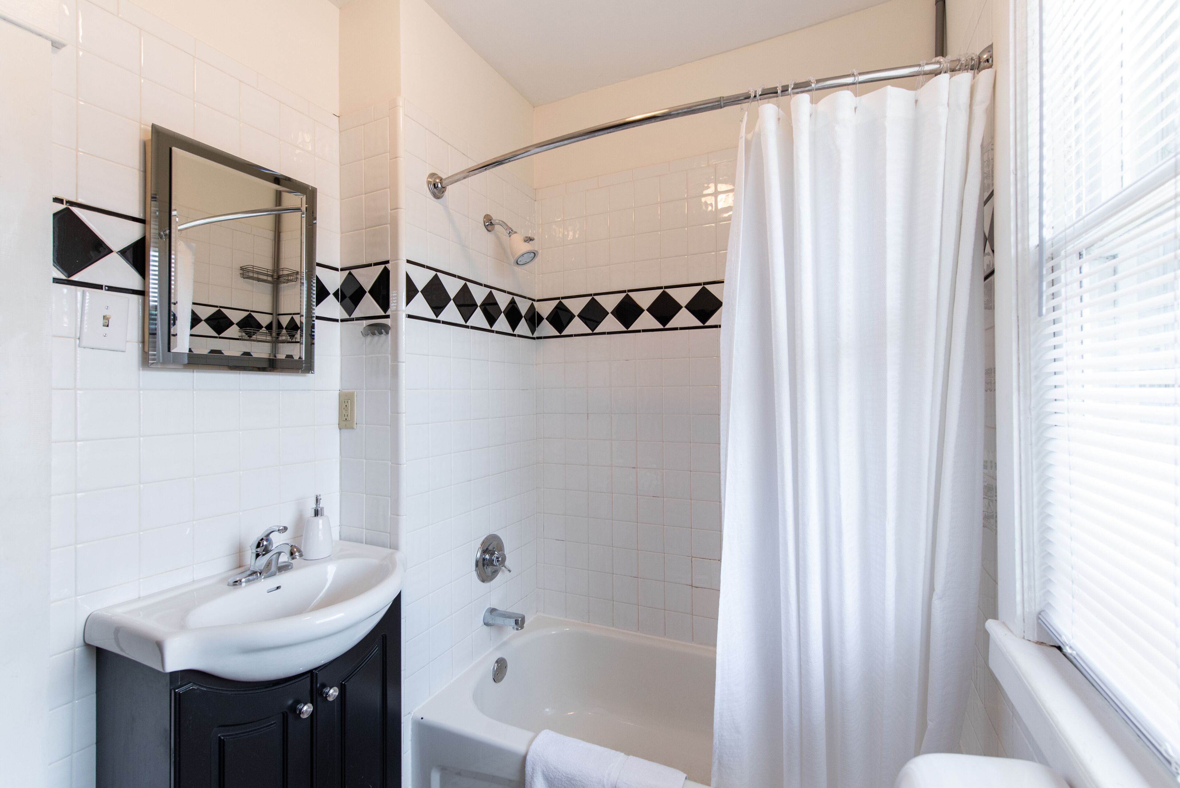 Une salle de bain avec un lavabo blanc, un miroir et une baignoire.