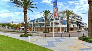 A modern hotel with a multi-story structure, a flag, and palm trees.
