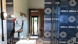A bathroom with a white sink, dark patterned tiles, a wooden cabinet, and a mirror with a decorative item. - Pipa Casa Mandacarú (Tibau do Sul)