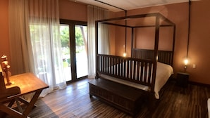 A bedroom with a four-poster bed, a wooden desk, and a view of greenery outside. - Pipa Casa Mandacarú (Tibau do Sul)