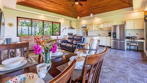 A spacious living area with a wooden ceiling, a dining table set with plates and cups, and a view of the kitchen in the background. - Don Pedro-Perfect for Couples & Families, Onsite Staff. (Savegre de Aguirre)
