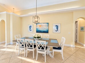 A dining area with a wooden table, white chairs, and a chandelier.