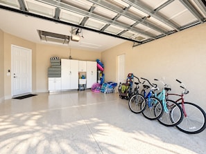 A garage with a concrete floor, white cabinets, and bicycles. - High End 4 Bdrm Heated Pool Walk To Gulf Walk To Mercato Walk To The Ritz (Naples)