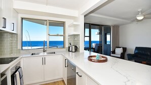 Une cuisine moderne avec vue sur l’océan, un coin repas offrant également une vue, et un ventilateur de plafond.