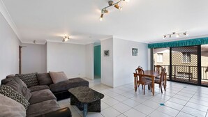 Uma sala de estar moderna com um sofá seccional, uma mesa de jantar com cadeiras e uma varanda com vista.