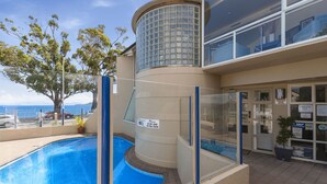 A pool area with a glass-enclosed section, a sign prohibiting hot tubs, and a view of the sea. - The Village Resort (Taupo)