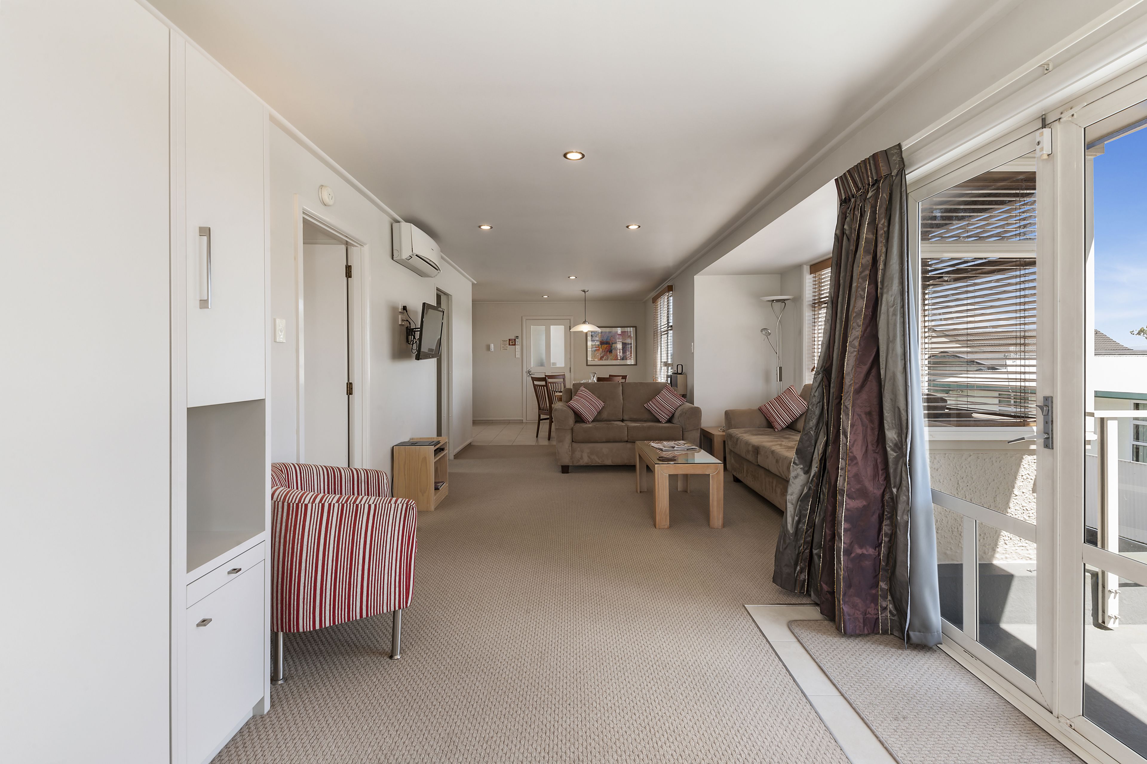 A spacious living area with a sofa, coffee table, and a view through a sliding glass door.