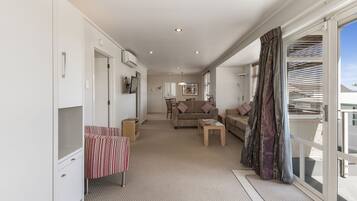 A spacious living area with a sofa, coffee table, and a view through a sliding glass door.