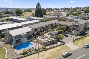 A modern residential complex with a swimming pool, multiple buildings, and a clear view of the surrounding area. - The Village Resort (Taupo)