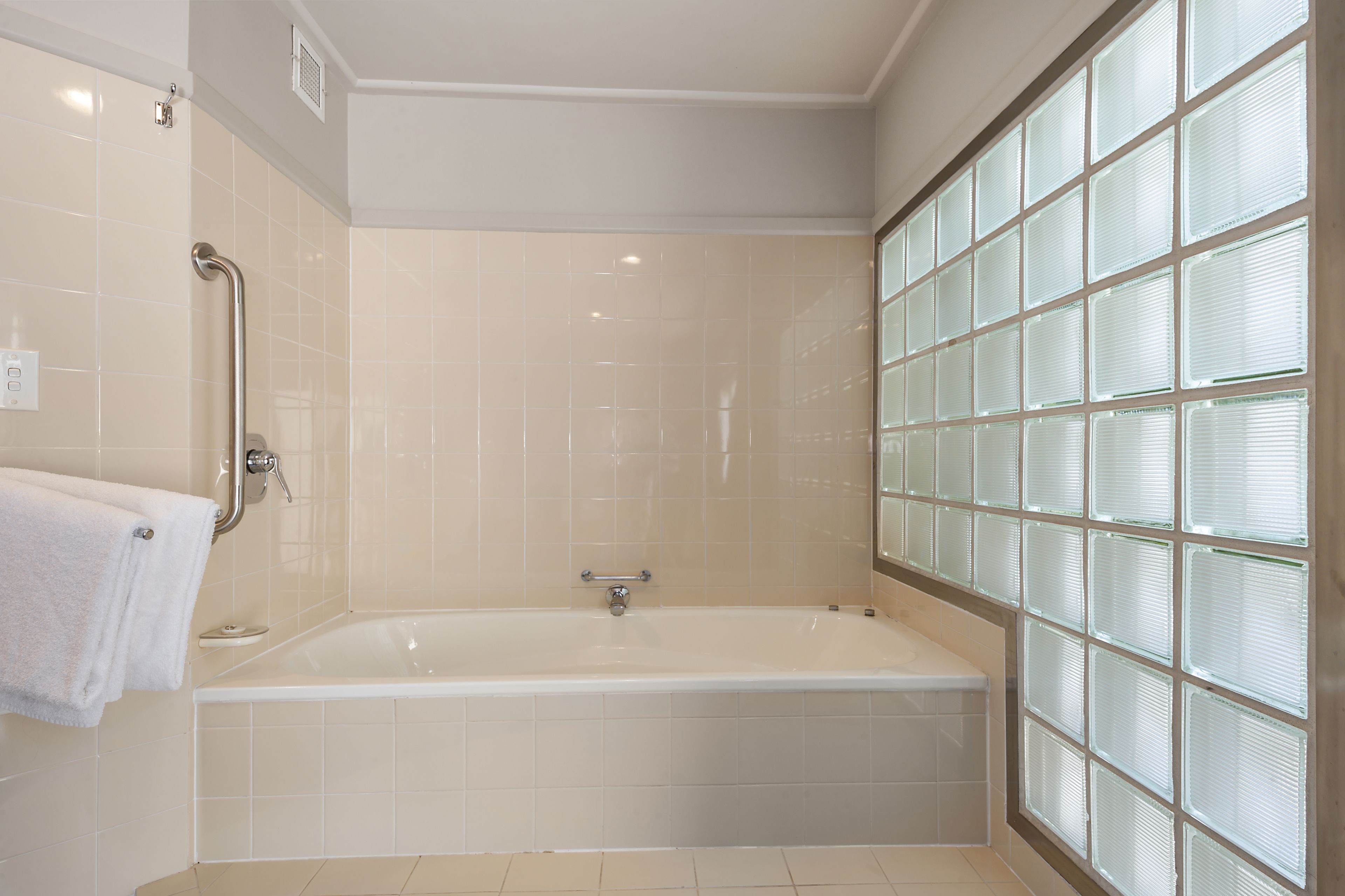 A modern bathroom with a bathtub, a glass shower enclosure, and a handrail.