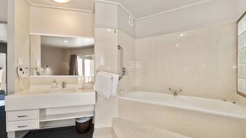 A modern bathroom with a large bathtub, a vanity with a mirror, and a shower area.