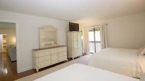 A bedroom with two beds, a dresser, a television on top of a cabinet, and a view of the outdoors through a window.