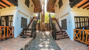 Una escalera simétrica que conduce a un árbol central, flanqueada por dos edificios con balcones y barandillas.