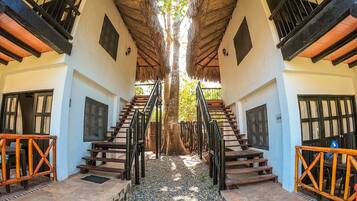 Una escalera simétrica que conduce a un árbol central, flanqueada por dos edificios con balcones y barandillas.
