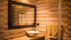 Un baño con pared de madera, un espejo grande, un lavabo blanco y una toalla colgada en la pared.