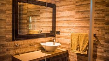 Un baño con pared de madera, un espejo grande, un lavabo blanco y una toalla colgada en la pared.